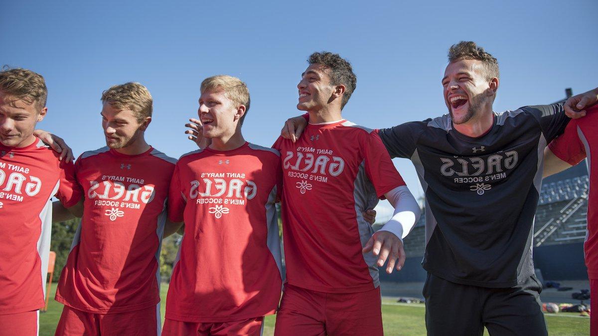 Men's soccer players smile in a huddle